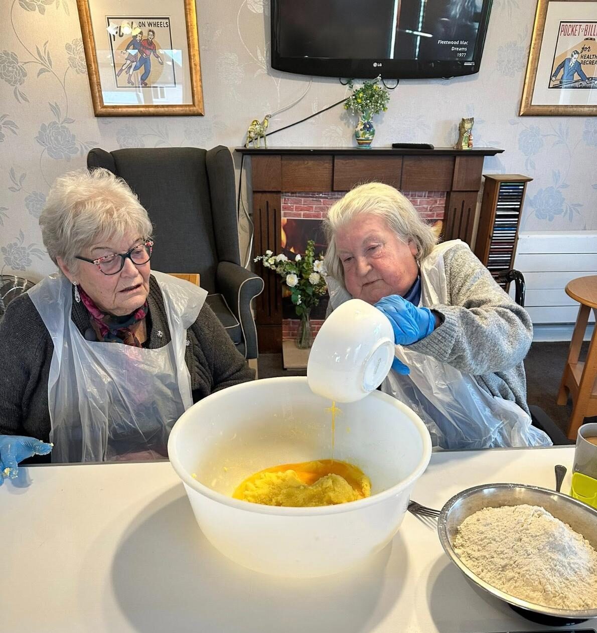 Care Home residents working together to measure ingredients in mixing bowl