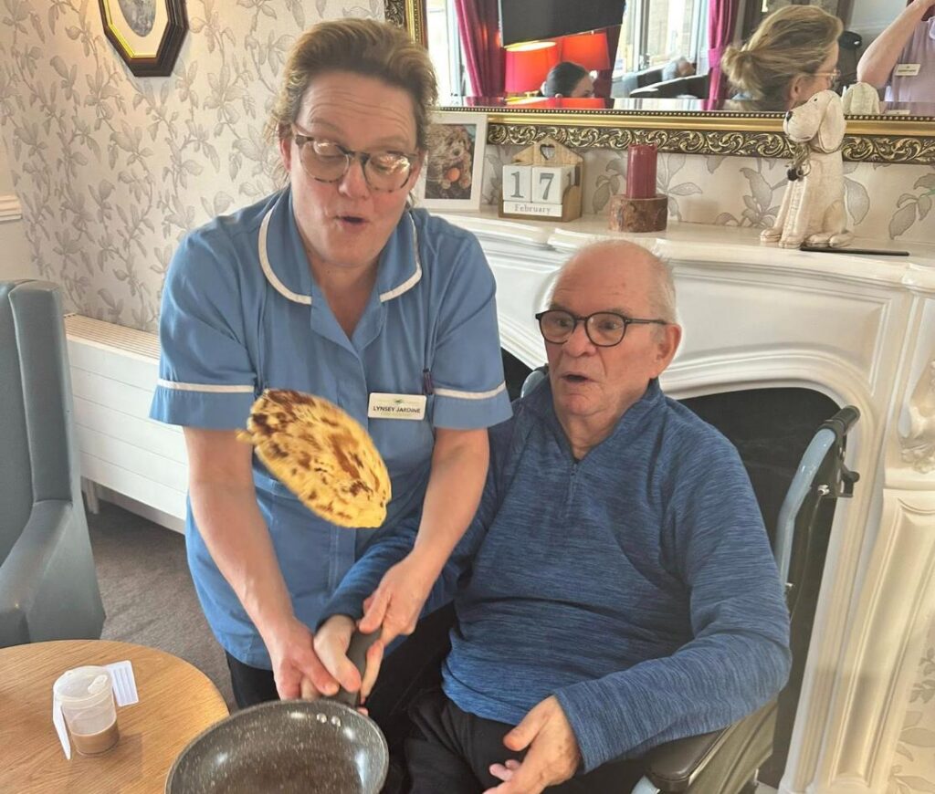 resident and staff member flipping a pancake