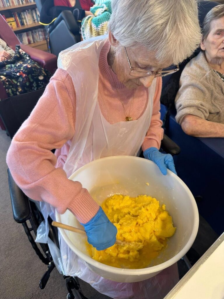 Woman in care home mixing together cookie dough
