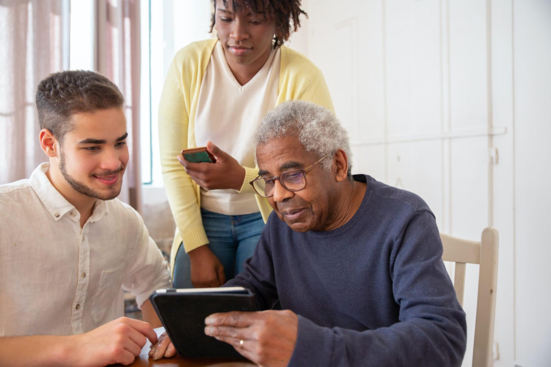 man helping elderly couple research care homes on a tablet