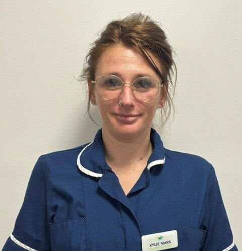 woman with brown hair in blue nurses uniform
