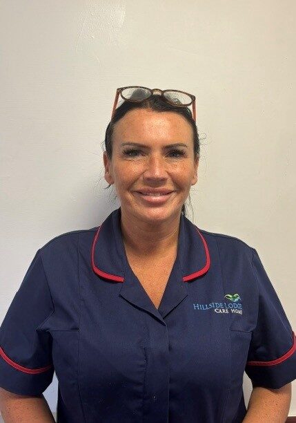 woman smiling in a navy blue nurses uniform