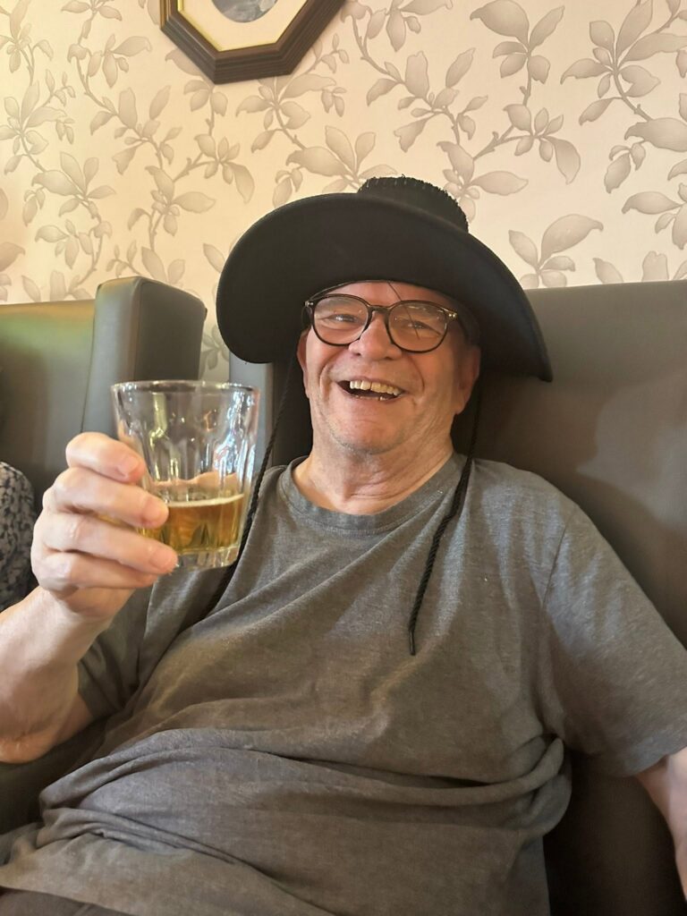 resident drinking whilst wearing a black hat