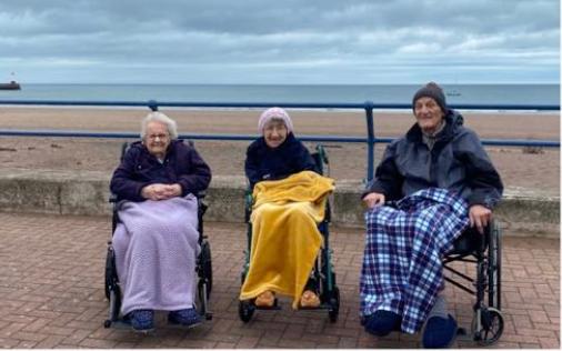 three residents on the beach with blankets